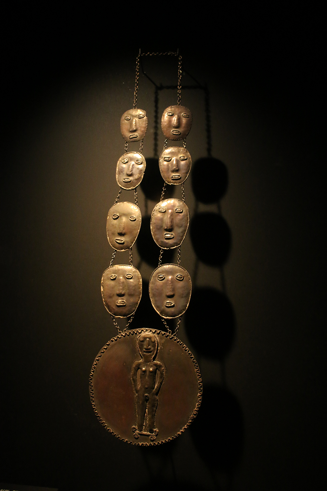 "Timor Leste", fotografía tomada no Museu do Oriente, Lisboa, o 1-6-23. Mostra un belak de ouro datado en 1930, un adobio tradicional que simboliza á lúa e a feminidade propio da cultura do Timor Leste, con luz dura sobre fondo escuro.